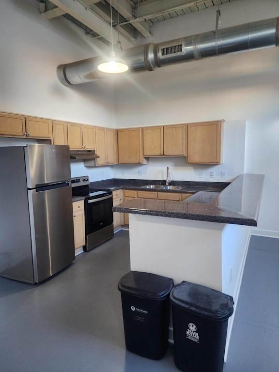 A kitchen with a stainless steel refrigerator, black trash cans, and wooden cabinets.