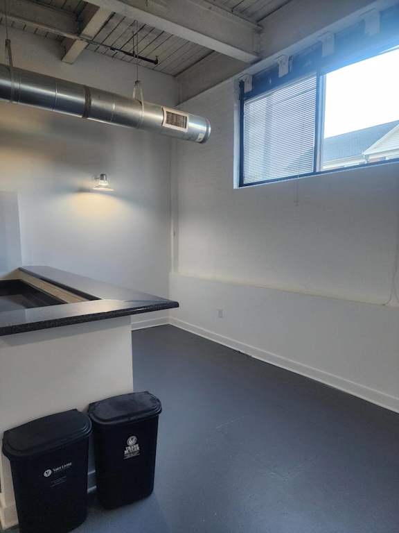 A room with a window, a counter, and two black bins.