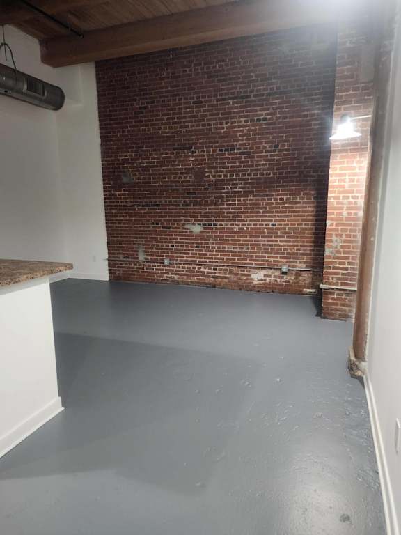 A room with a brick wall and a concrete floor.