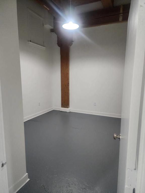 A room with a white wall and a wooden beam.