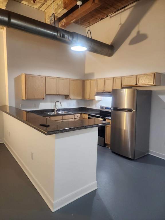 A kitchen with a stainless steel refrigerator and a black countertop.