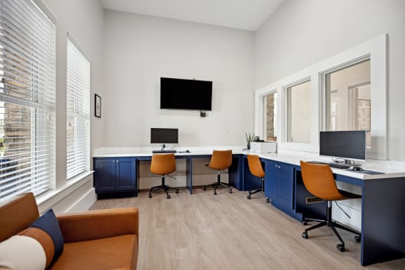 a room with a desk and chairs and a tv on the wall
