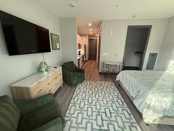 A bedroom with a bed, a couch, a chair, and a cabinet.