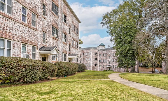 A large brick building with a green lawn in front.