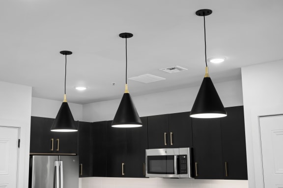 a kitchen with black cabinets and a stainless steel refrigerator and black pendant lights hanging from the at Preston Centre, Columbus, 43215