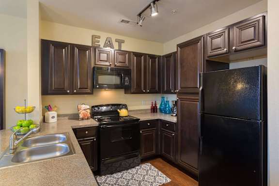 A kitchen with a black refrigerator and a black stove.