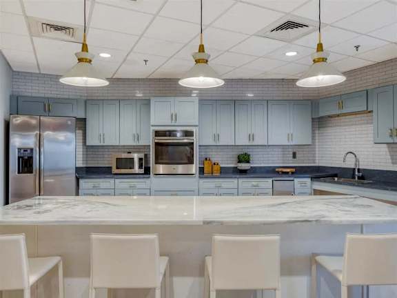 A kitchen with a white island and white chairs.