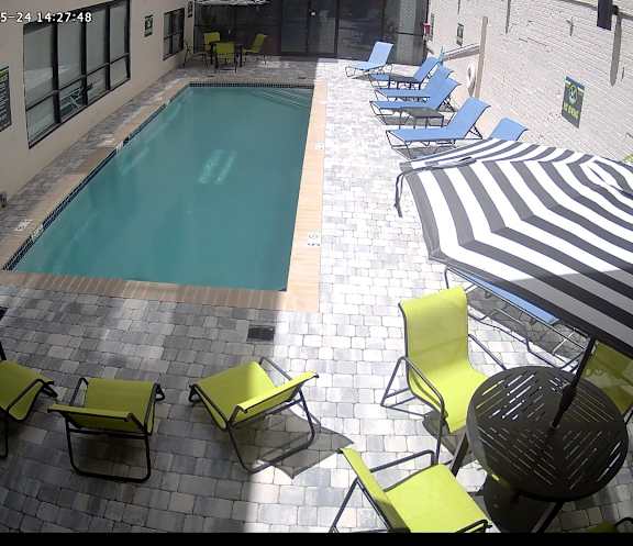 A pool surrounded by chairs and umbrellas.