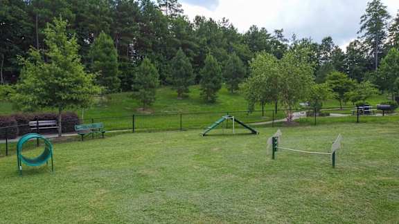 A playground with a green slide and a green swing set.