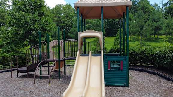 A playground with a yellow slide and a green roofed structure.