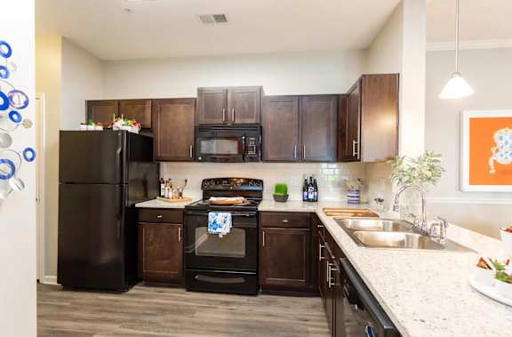 A kitchen with black appliances and brown cabinets.