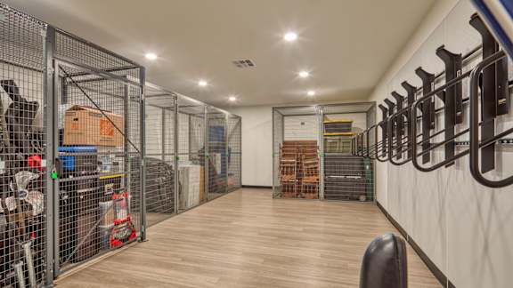 A storage room with a wooden floor and white walls, containing various items and storage units.