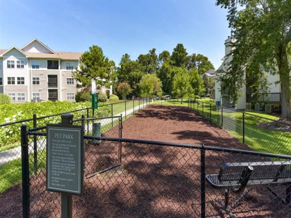 a park with a bench and a sign in front of a fence