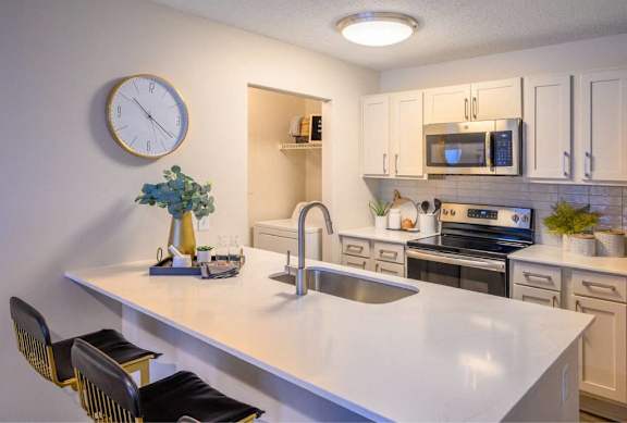 A kitchen with a white countertop and a clock on the wall.