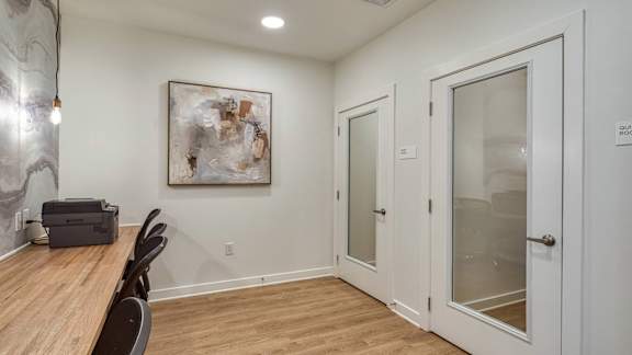 A room with a wooden table and chairs, a painting on the wall, and a glass door.
