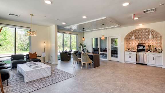 A well-lit, spacious living room with a kitchen area in the background.