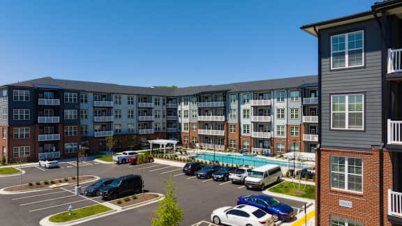 A parking lot with cars and apartment buildings in the background.