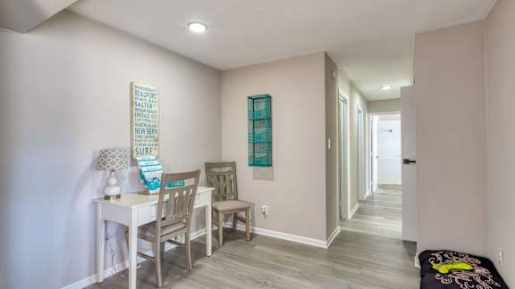 a dining room with a table and chairs and a hallway with a door at Bayville Apartments, Virginia Beach