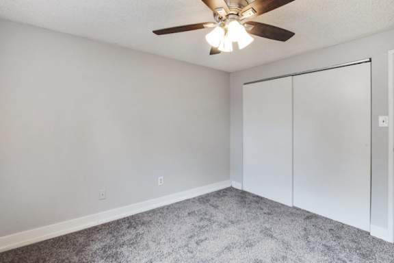 A room with a ceiling fan and carpeted floor.