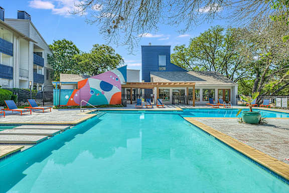 Pool deck with lounge chairs and abstract mural at Peaks @ NW Hills Apartments, Texas