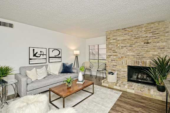 Contemporary living room with brick fireplace and gray sofa at Peaks @ NW Hills Apartments, Austin