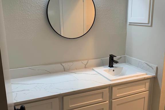 Bathroom sink with marble backsplash and black fixtures at Peaks @ NW Hills Apartments, Austin, TX