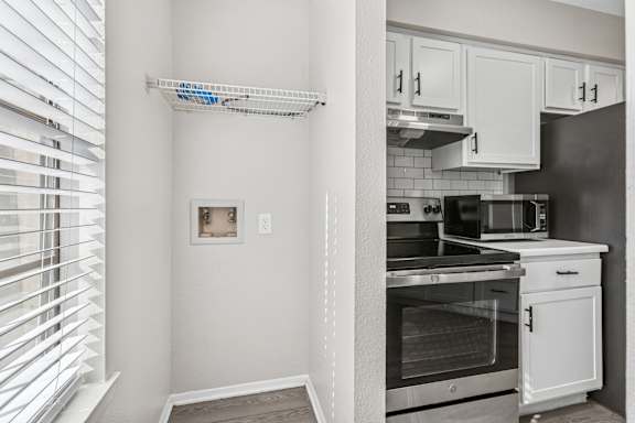 Laundry area with overhead storage and window blinds at Polo Club Apartments, Austin, TX 78729
