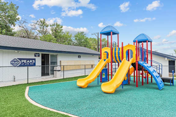 Playground area with slides and climbing equipment at Peaks at Live Oak Apartments, San Antonio, TX 78233