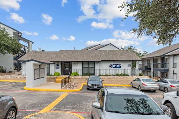 Leasing office building with mailbox kiosk and parking lot at Peaks at Live Oak Apartments, Texas