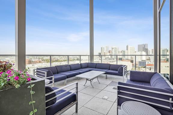 A patio with a couch, chairs, and a table with a view of the city.