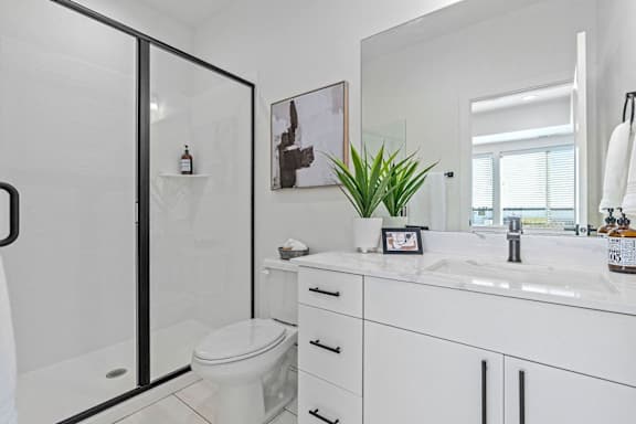 a white bathroom with a shower, a toilet, and a sink