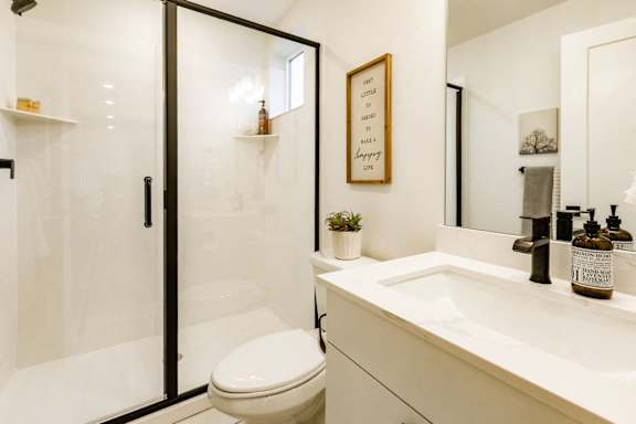 bathroom with a toilet, sink, mirror, and shower