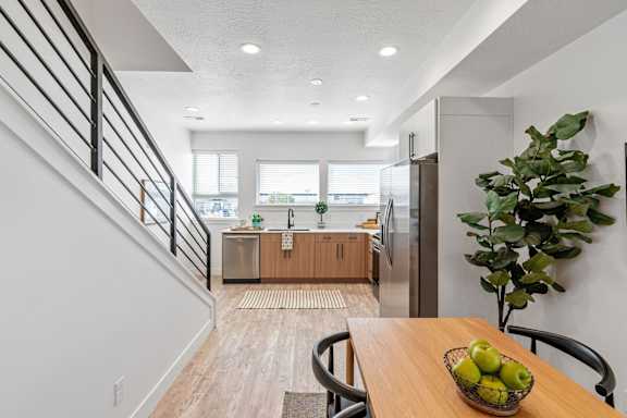 an open kitchen and dining room with a table and a bowl of fruit