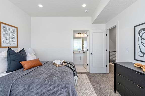 bedroom with a bed and dresser and a door leading to a bathroom