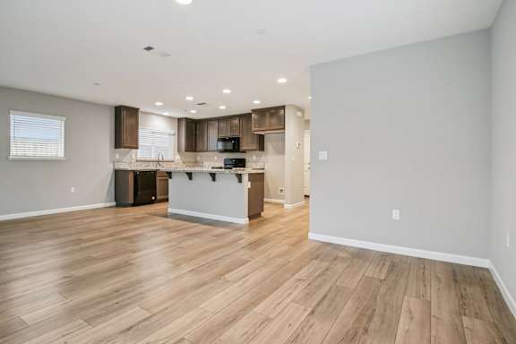 A spacious kitchen with wooden floors and white walls.