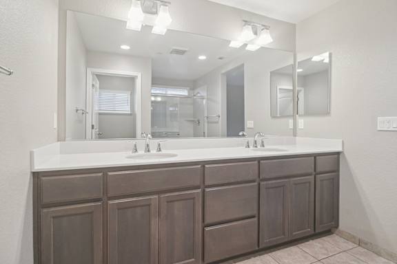 Primary bathroom with a brown vanity and a large mirror.