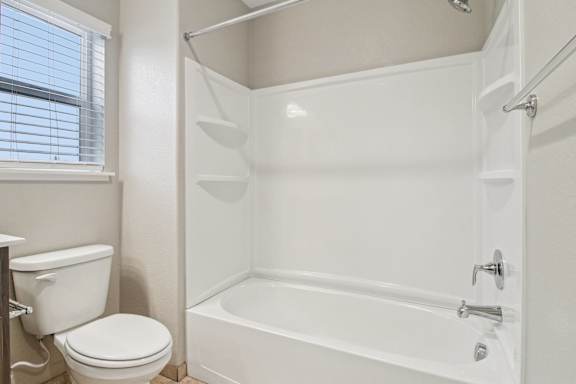 A white bathroom with a toilet, tub, and shower.