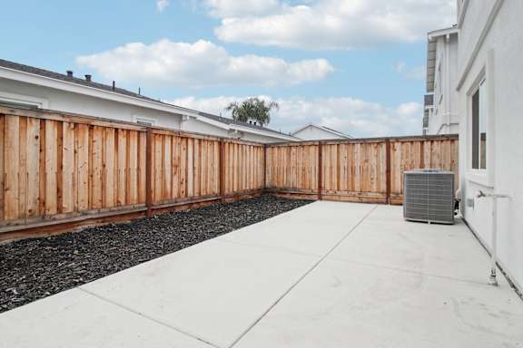 A backyard with a wooden fence and a white wall.