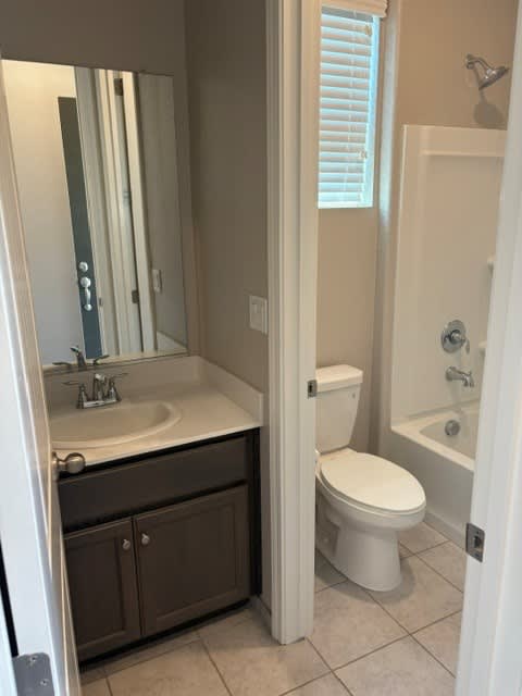 A white toilet is in a bathroom with a sink and mirror.