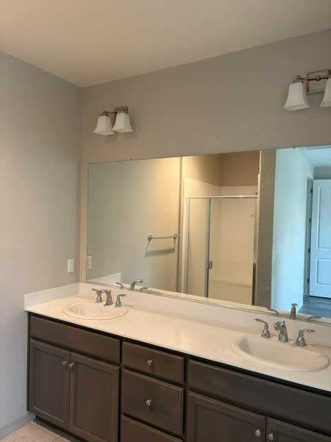 A bathroom with a white sink and brown cabinets.
