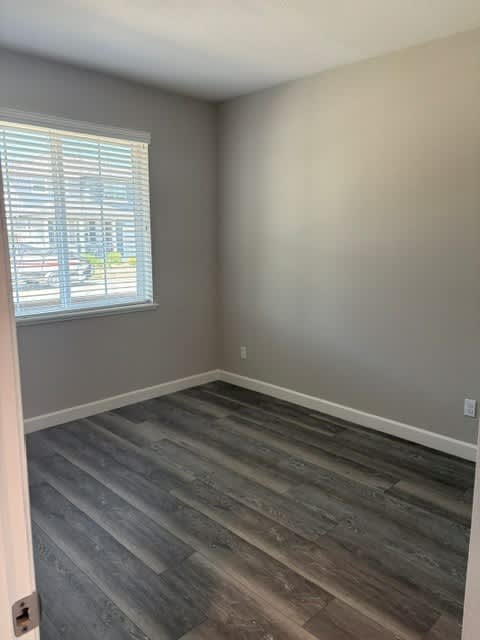 A room with a window and wooden flooring.