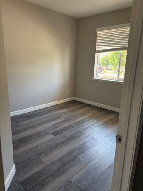 A room with a window and wooden flooring.