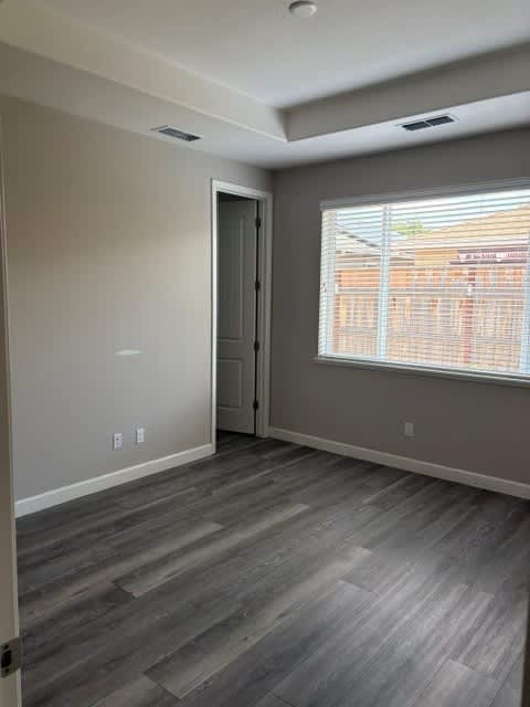 A room with a grey floor and a window with blinds.