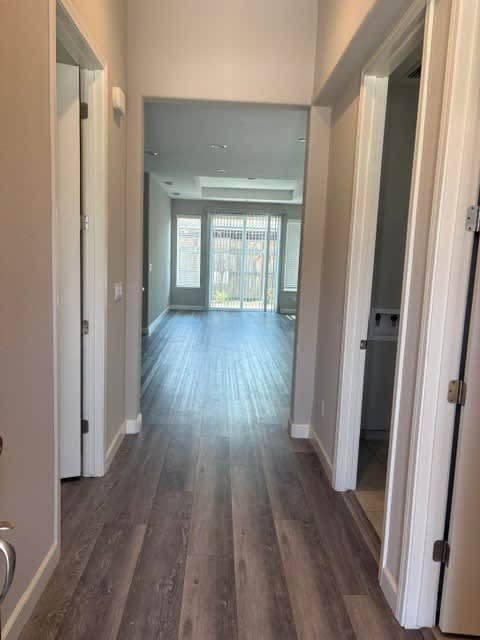 A long hallway with white walls and wood flooring.