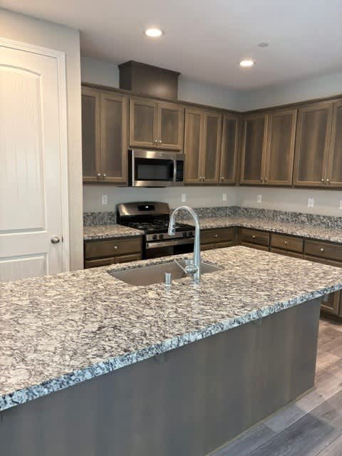 A kitchen with granite countertops and wooden cabinets.