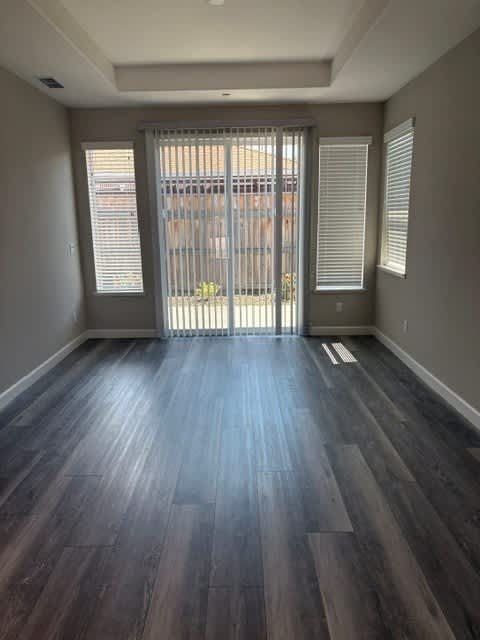 A room with a sliding glass door and dark wood flooring.