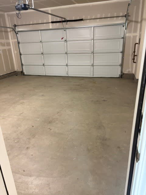 A garage with a white door and a concrete floor.