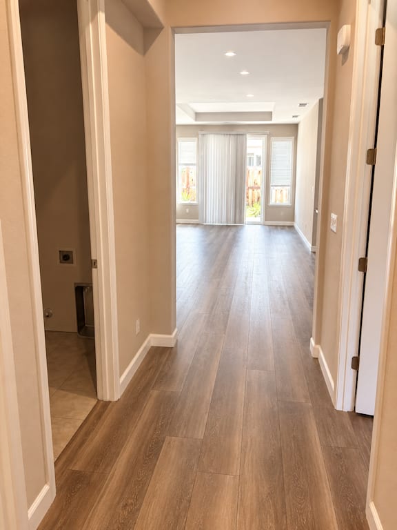 A long hallway with wood floors and white walls.