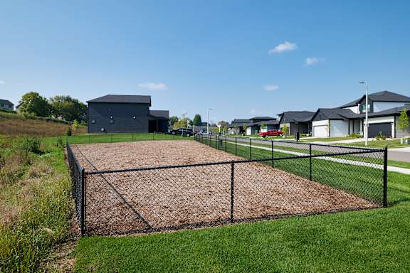 A baseball field with a black fence and a brown diamond plate.