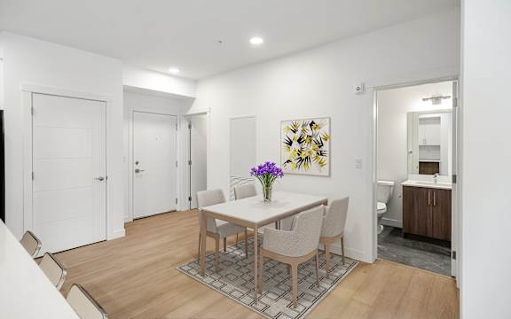 A dining room with a table and chairs and a painting on the wall.